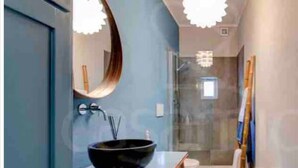 Een moderne badkamer met een ronde spiegel, een zwart wastafel en een douchecabine van glas.