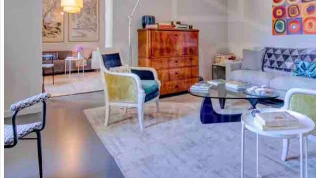 Een moderne woonkamer met een bank, stoelen, een salontafel en een houten kast.