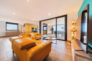 Ein modernes Wohnzimmer mit einer großen Couch, einem Essbereich und einer Küche im Hintergrund.