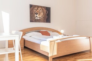 A bedroom with a wooden bed, white bedding, a desk, and a chair. - Cozy Rooms Perfect for Extended Stays (Vienna)