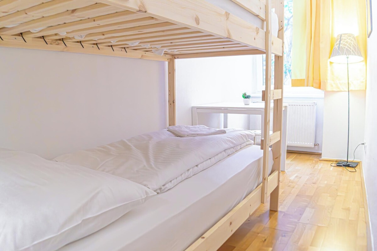 A bunk bed room with a wooden ceiling, a small table with a plant, and a lamp.