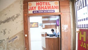 A hotel entrance with a reception desk, a sign indicating 'HOTEL JAY BHAWANI A/C. NON A/C ROOM,' and a partially visible interior wall. - HOTEL JAY BHAWANI (Ahmedabad)