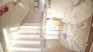 A staircase leading to the 1st floor with a metal handrail, signs for Hotel Jay Bhawan and Hotel Sky, and a wall with peeling paint. - HOTEL JAY BHAWANI (Ahmedabad)