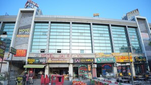 A hotel with multiple floors, outdoor seating, and various signs in multiple languages. - HOTEL JAY BHAWANI (Ahmedabad)