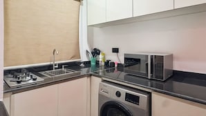 A compact kitchen with a washing machine, a microwave, and a sink. - Monica Apartment (Abuja)