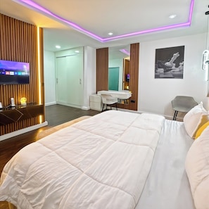 A modern bedroom with a large bed, a desk, and a TV mounted on the wall. - Monica Apartment (Abuja)