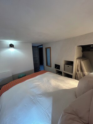 A hotel room with a large bed, a bedside table, a nightstand, a mirror, and a ceiling light. - Old sheep barn with a private pool (Bonnieux)