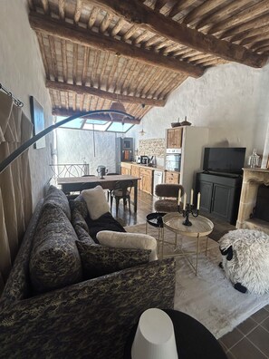 A cozy living room with a sofa, a small round table, and a television. - Old sheep barn with a private pool (Bonnieux)