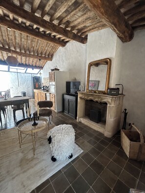 Ein rustikales Interieur mit Kamin, Holzbalken, einer Essecke und einem großen Spiegel.