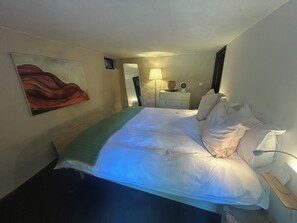 Ein Hotelzimmer mit einem Bett, einem Nachttisch, einer Lampe und einem Bild an der Wand.