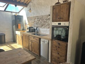 Cocina compacta con armarios de madera, lavavajillas integrado y una pared de acento de piedra.