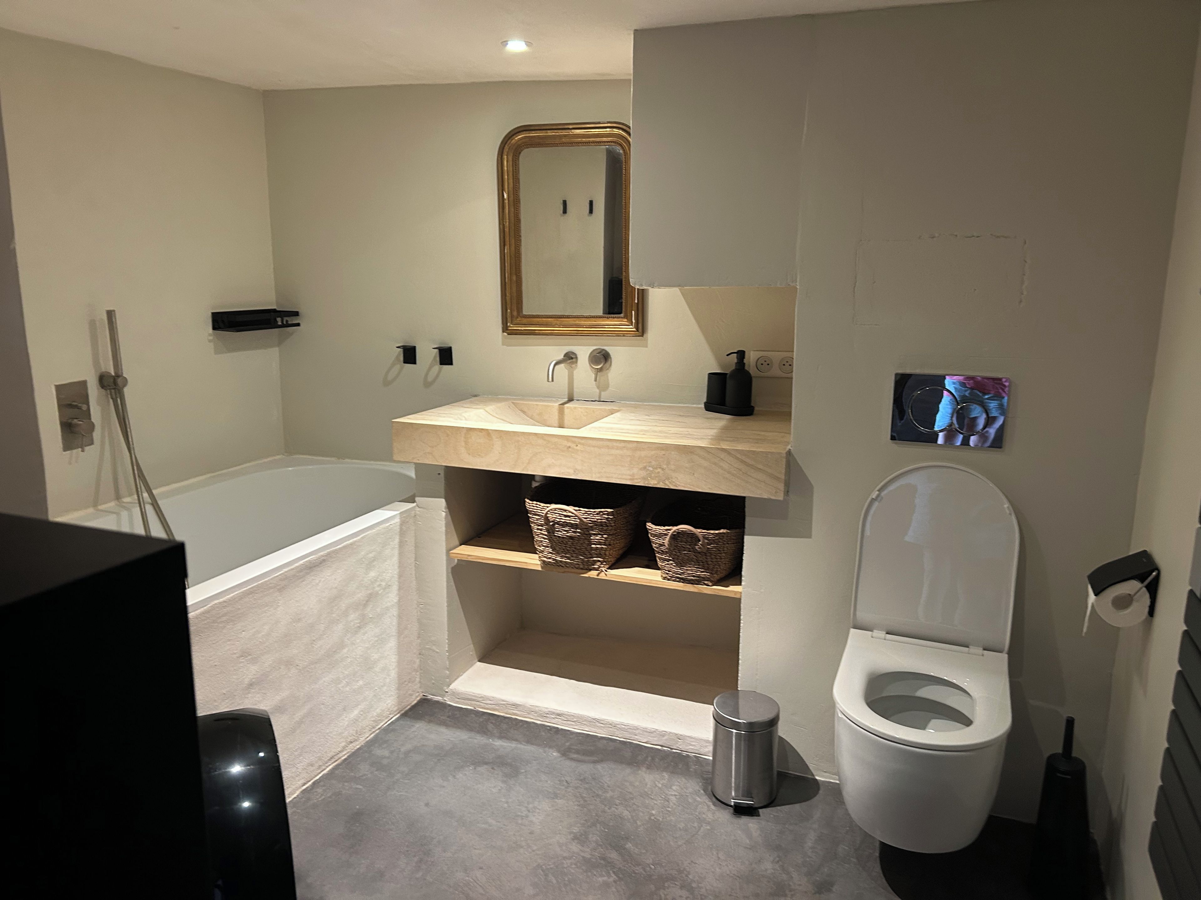 A modern bathroom with a bathtub, toilet, and vanity.