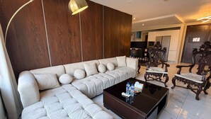 Un soggiorno moderno con un divano componibile, un tavolino in vetro e poltrone in legno intagliato.