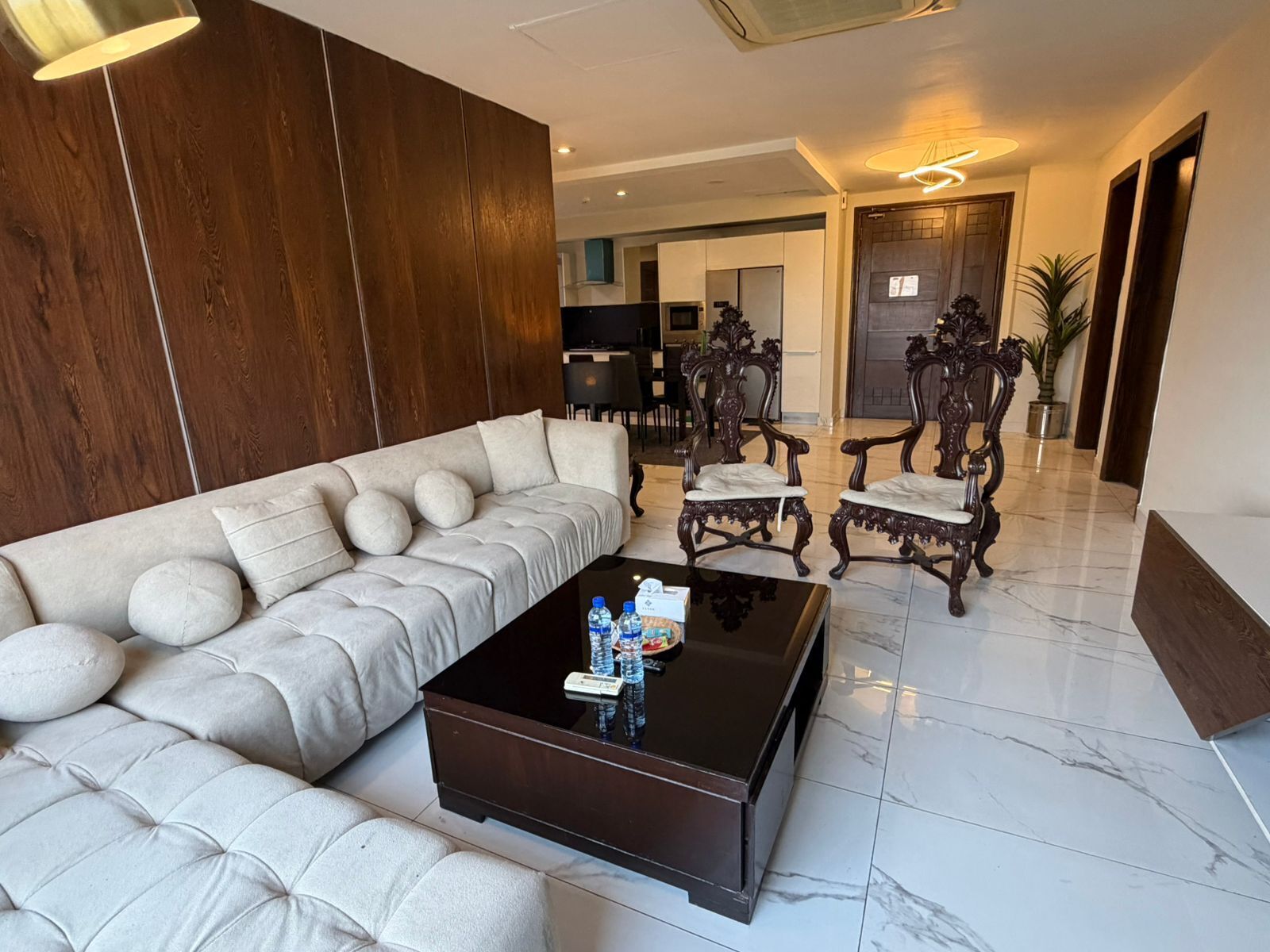 A modern living room with a sectional sofa, a coffee table, and ornate wooden chairs.
