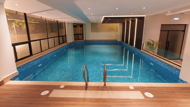 Una piscina interna con acqua cristallina, pavimento in legno e design moderno.