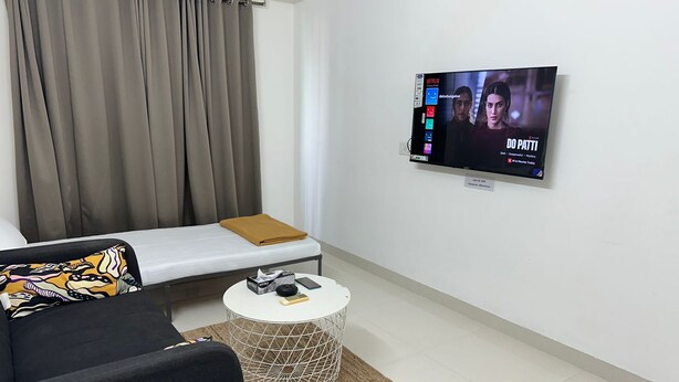 Ein modernes Wohnzimmer mit einer Couch, einem Couchtisch und einem an der Wand befestigten Fernseher.