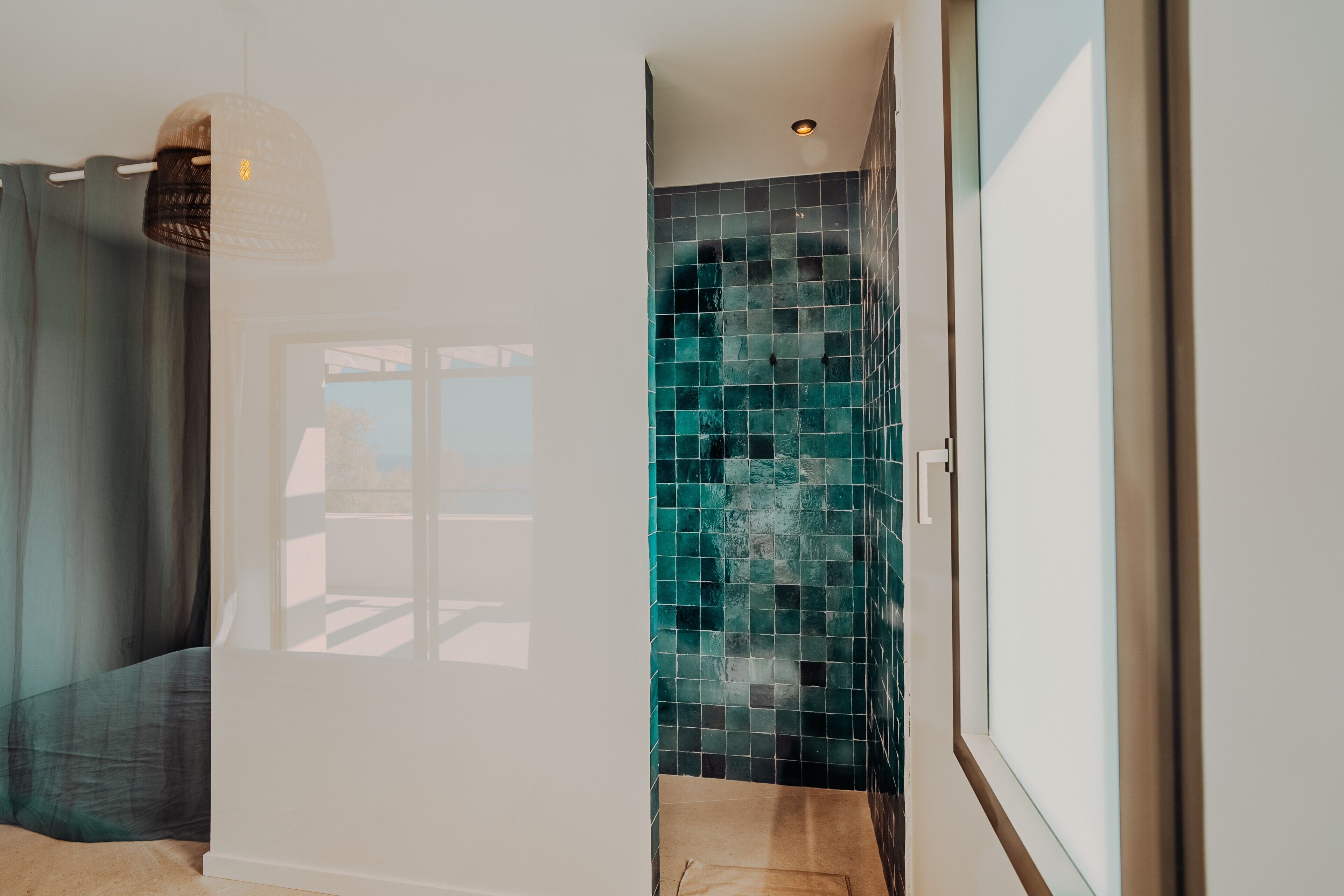 Un baño con pared de azulejos, ventana y zona de ducha.