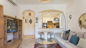 Un salon moderne avec un téléviseur, un canapé et une table ronde en verre.