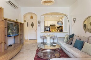 A modern living room with a TV, sofa, and round glass table. - Vesta - Luxury APT - 3BR - South Marina (El Gouna)