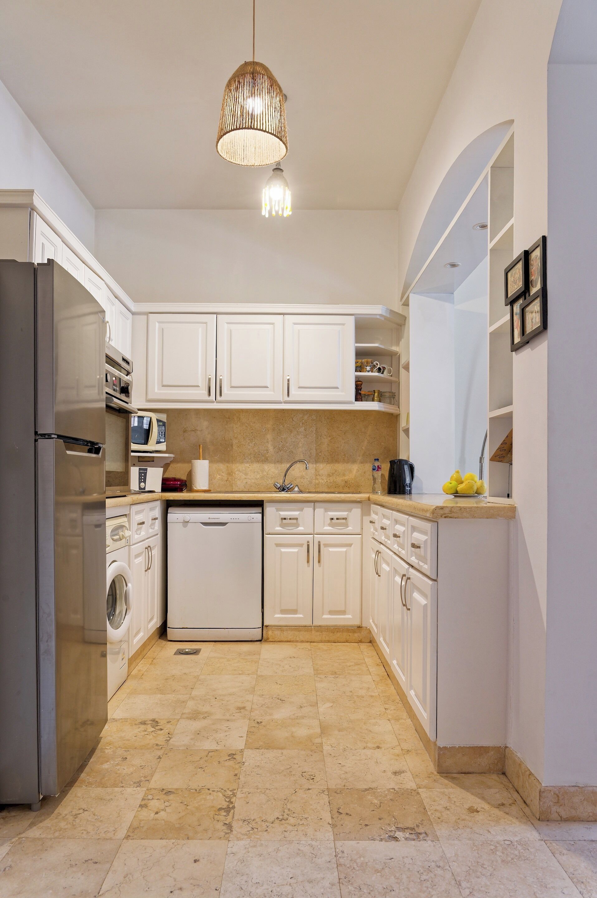 A modern kitchen with white cabinets, a stainless steel refrigerator, a dishwasher, and a microwave.