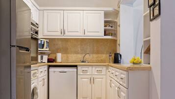 A modern kitchen with white cabinets, a stainless steel refrigerator, a dishwasher, and a microwave.