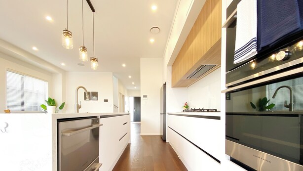 Une cuisine moderne dotée d’appareils électroménagers en acier inoxydable, de planchers en bois et de luminaires suspendus.