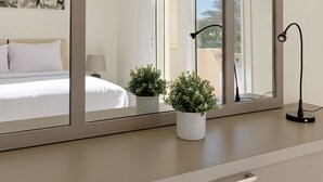 A bedroom with a large mirror, a bed with white bedding, a bedside table with a lamp, and a potted plant. - Vesta - Luxury Villa - 4BR - Joubal (El Gouna)