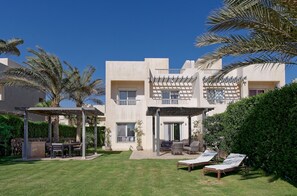 A modern building with a covered outdoor seating area, a pool, and lounge chairs. - Vesta - Luxury Villa - 4BR - Joubal (El Gouna)