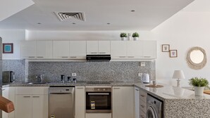 A modern kitchen with white cabinets, granite countertops, a dishwasher, an oven, and a washing machine. - Vesta - Luxury Villa - 4BR - Joubal (El Gouna)