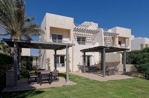 A modern building with a covered patio area, outdoor seating, and a well-maintained lawn. - Vesta - Luxury Villa - 4BR - Joubal (El Gouna)