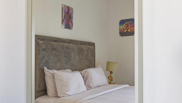A bedroom with a bed, nightstand, and wall art. - Vesta - Luxury Villa - 4BR - Joubal II (El Gouna)