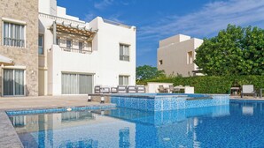 A modern hotel with a swimming pool, outdoor seating, and a lush green backdrop. - Vesta - Luxury Villa - 4BR - Joubal II (El Gouna)