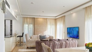 A modern living room with a sectional sofa, a dining table, and a kitchen area. - Vesta - Luxury Villa - 4BR - Joubal II (El Gouna)