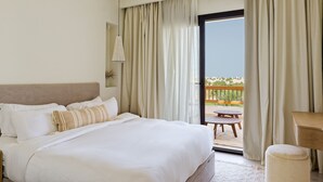 Habitación de hotel con cama, una mesita y balcón con cortinas.