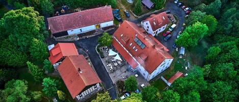 Vista aérea de un complejo de edificios rodeado de abundante vegetación, con varias construcciones con tejados rojos y un patio central.