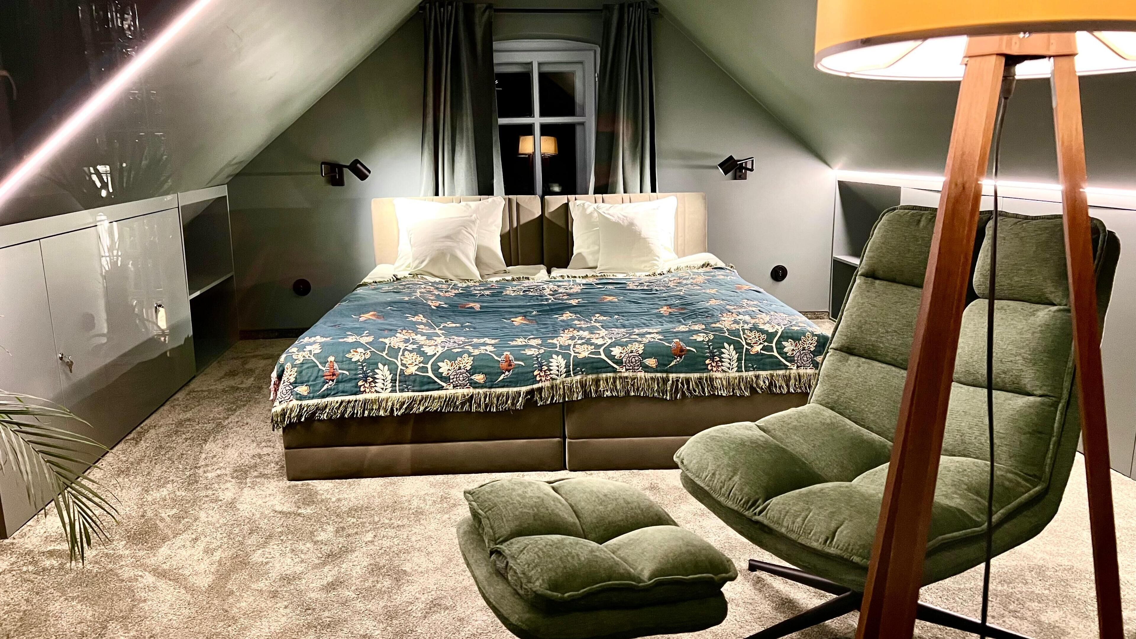 A bedroom with a bed, a chair, a lamp, and a window with curtains.