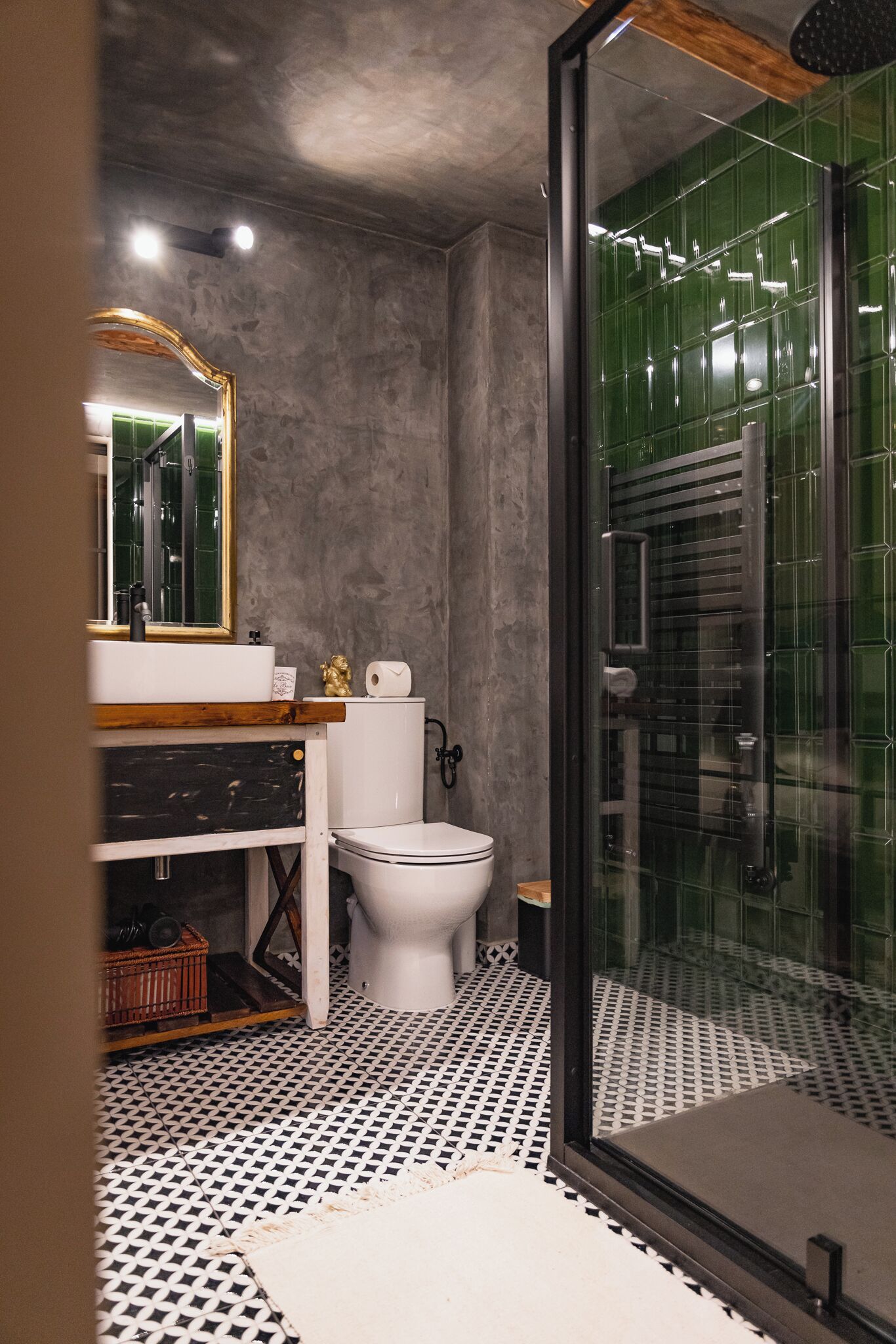 Een badkamer met een wit toilet, een houten wastafelmeubel, een spiegel en een douchecabine met glazen wanden.