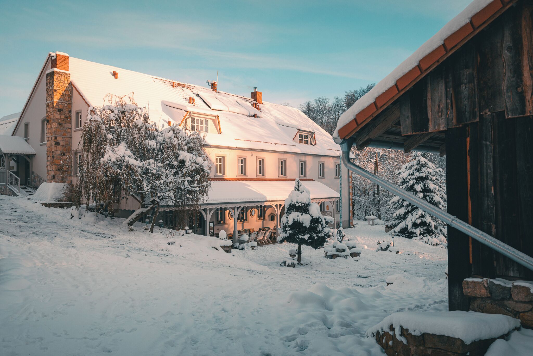 A large house with a snow-covered roof and a stone chimney.
