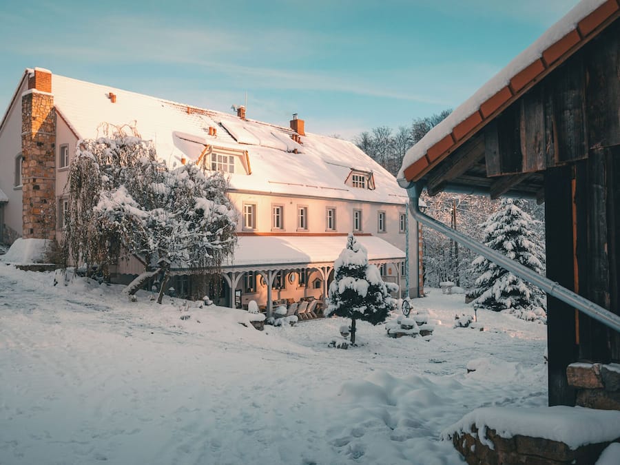 A large house with a snow-covered roof and a stone chimney.