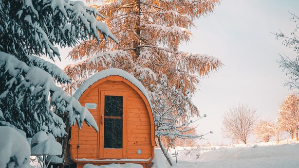A wooden cabin with a snow-covered roof, surrounded by snow-laden trees and a clear sky. - Turkusowa Wyspa (Wlen)