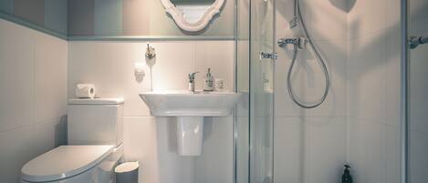 A modern bathroom with a toilet, sink, and glass-enclosed shower.