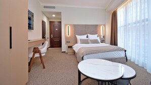 Une chambre d’hôtel moderne, dotée d’un grand lit, de tables de chevet, d’un bureau et d’une chaise.