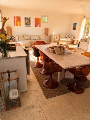 Ein modernes Wohnzimmer mit Essbereich, ausgestattet mit einem großen Holztisch und passenden Stühlen, einer Sofagarnitur und Bildern an den Wänden.