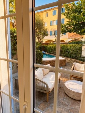 An outdoor patio area with stone flooring, a pool, and lounge furniture.