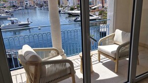 A balcony with wicker chairs, a view of a marina with boats, and buildings in the background. - Charming villa Port Grimaud - Swimming pool - Mooring - Boats (port grimaud)