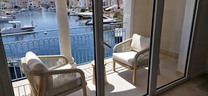 A balcony with wicker chairs, a view of a marina with boats, and buildings in the background. - Charming villa Port Grimaud - Swimming pool - Mooring - Boats (port grimaud)