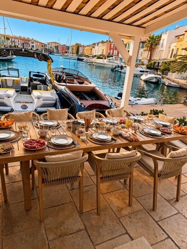 An outdoor dining area with a view of a marina and boats. - Charming Villa in Port Grimaud - Pool - Boat Dock - Boats (port grimaud)