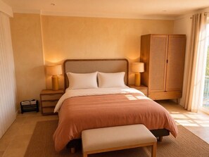 A bedroom with a bed, bedside lamps, a bench, a wardrobe, and a window with curtains. - Charming Villa in Port Grimaud - Pool - Boat Dock - Boats (port grimaud)