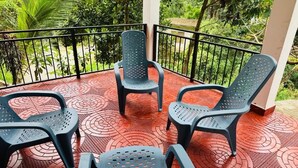 A balcony with four black plastic chairs and a table, surrounded by a red patterned floor and a black railing. - Room-charming 3-bedroom Apartment With G (Kandy)