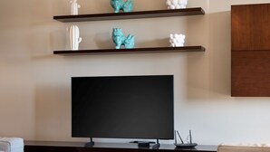 Een moderne woonkamer met een flatscreen televisie, houten planken en een bank.
